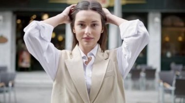 Young beautiful hispanic woman smiling confident combing hair with hands at street