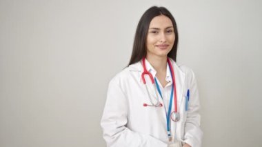 Genç, güzel İspanyol kadın doktor gülümsüyor, izole beyaz arka plan üzerinde yan tarafı işaret ediyor.