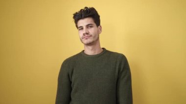 İzole edilmiş sarı arka planda duran kendine güvenen İspanyol genç adam.
