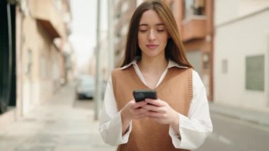 Sokakta akıllı telefon kullanan, kendine güvenen genç İspanyol kadın.