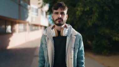 Sokakta kulaklık takarak gülümseyen İspanyol genç adam.