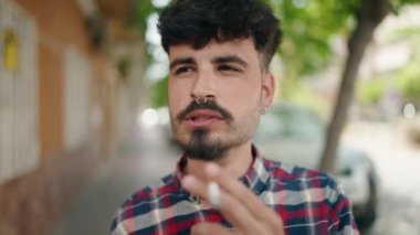 Young hispanic man smoking at street