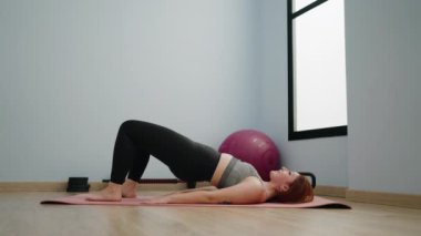 Genç kızıl saçlı kadın gülümsüyor spor merkezinde kendine güvenen yoga eğitimi alıyor.