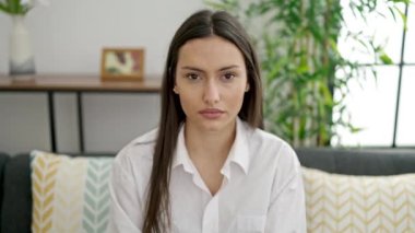 Kanepede oturan genç ve güzel İspanyol kadın ciddi bir ifadeyle ve evde jesti durdurun.