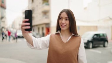 Young hispanic woman smiling confident having video call at street