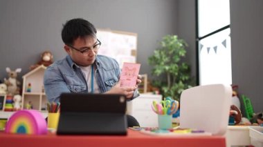 Young chinese man preschool teacher having online vocabulary lesson at kindergarten
