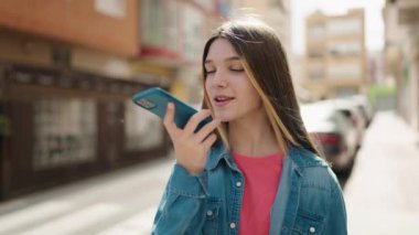 Adorable girl smiling confident talking on the smartphone at street