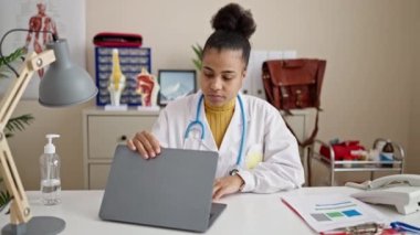 Genç Afrikalı Amerikalı kadın doktor klinikte laptopunu kullanıyor.
