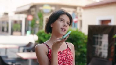 Sevimli İspanyol kız gülümsüyor. Kendine güveni tam. Sokakta akıllı telefondan konuşuyor.