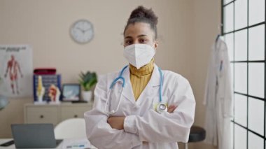 Genç Afrikalı Amerikalı kadın doktor gülümsüyor. Klinikte maske takıyor ve kendine güveniyor.