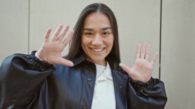 Genç, güzel İspanyol kadın gülümsüyor. Kendine güvenen, elleri izole beyaz arka planda hareket eden.