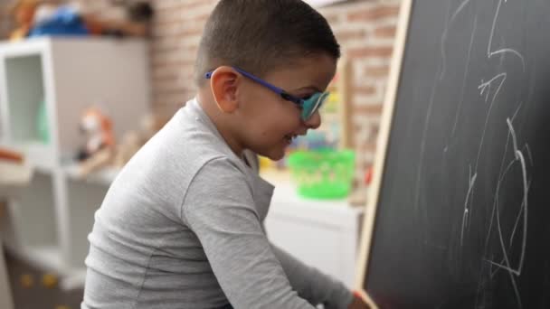 Uroczy Latynoski Uczeń Uśmiecha Się Pewnie Rysując Tablicy Przedszkolu — Wideo stockowe
