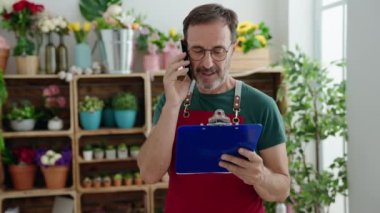 Ortaçağ çiçekçisi çiçekçide akıllı telefondan pano okuyor.
