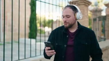 Young plus size man listening to music and dancing at street