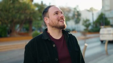 Genç ve cüsseli bir adam gülümsüyor. Kendine güveniyor.