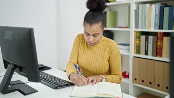 図書館でノートを取るコンピュータを使用して若いアフリカ系アメリカ人女性の学生 — ストック動画