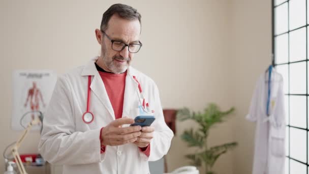 Homme Âge Moyen Médecin Souriant Confiant Utilisant Smartphone Clinique — Video