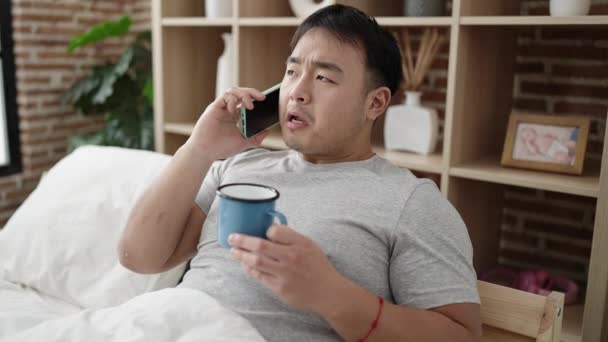 Молодой Китаец Разговаривает Смартфону Пьет Кофе Спальне — стоковое видео