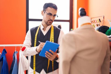 Genç İspanyol terzi atölyede dokunmatik bir ceket çiziyor.