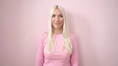 Young blonde woman smiling confident standing over isolated pink background