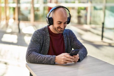 Genç adam kendinden emin bir şekilde kahve dükkanının terasında müzik dinliyor.