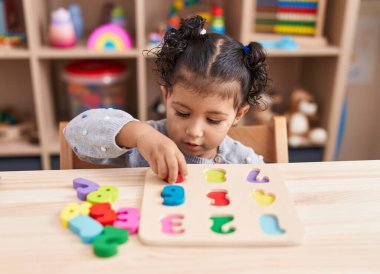 Anaokulunda masada oturmuş matematik oyunu oynayan sevimli İspanyol kız.