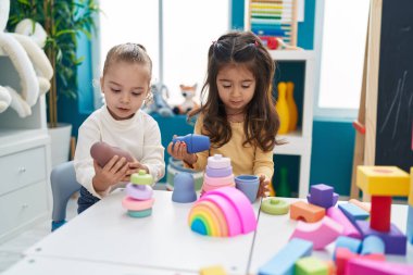 Anaokulundaki masada oturan inşaat bloklarıyla oynayan sevimli kızlar.