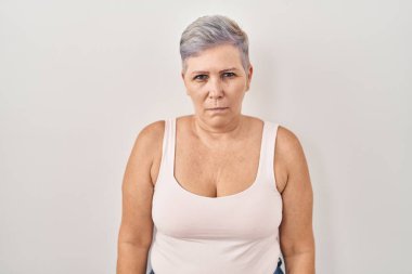 Beyaz arka planda duran orta yaşlı beyaz kadın şüpheci ve gergin, sorun yüzünden surat asıyor. negatif kişi. 