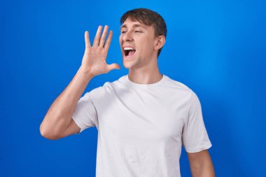 Beyaz, sarışın bir adam mavi arka planda durup el pençe divan çığlıklar atıyordu. iletişim konsepti. 