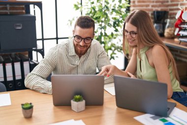 Man and woman business workers using laptop speaking at office