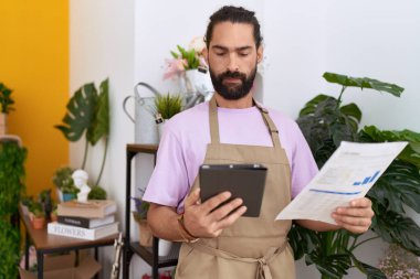 Çiçekçide dokunmatik kağıt okuyan İspanyol bir çiçekçi.