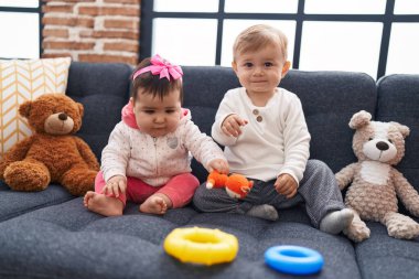 Sevimli kız ve oğlan evdeki kanepede oturup basketbol oynuyorlar.