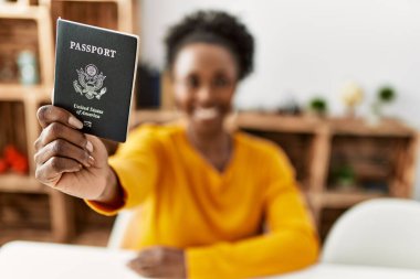 African american woman holding united states passport sitting on table at home