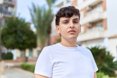 İkili olmayan adam parkta ciddi bir ifadeyle duruyor.