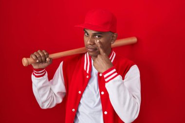 Beyzbol oynayan genç İspanyol bir adam elinde sopayla gözüne bakıyor ve senin jestini izliyor. Şüpheli bir ifade. 