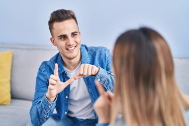 Erkek ve kadın çift evdeki koltukta oturan sağırlarla iletişim kuruyor.