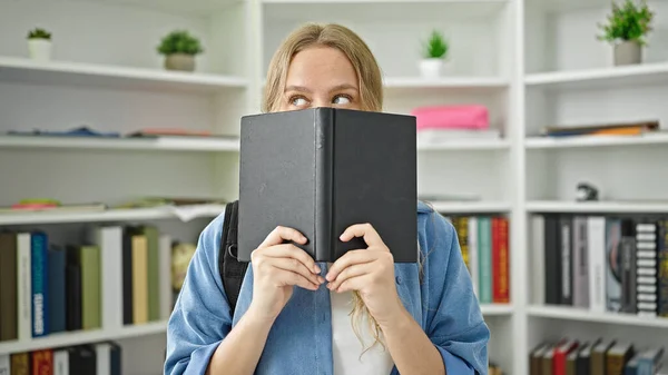 Joven Estudiante Rubia Pie Cubriendo Cara Con Libro Biblioteca Universidad —  Fotos de Stock