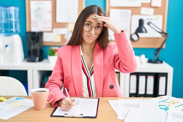 オフィスで働く若いヒスパニック系の女性が眼鏡をかけて心配し 額に手で問題について強調しました 危機への神経と不安 — ストック写真