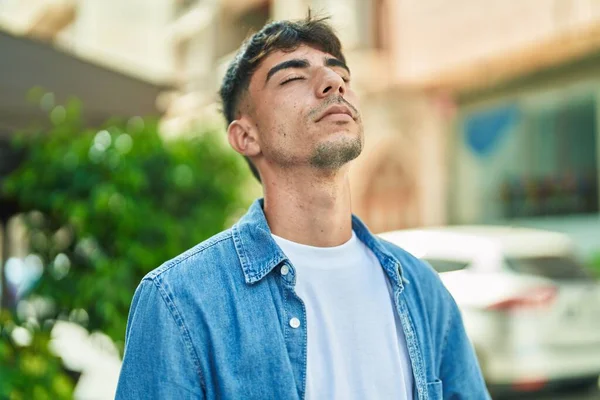 Young hispanic man breathing with closed eyes at street