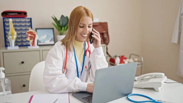 Young Blonde Woman Doctor Using Laptop Talking Smartphone Clinic — Stock Photo, Image