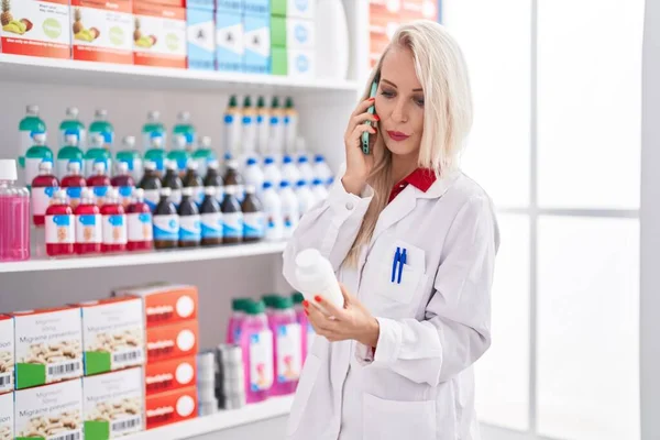 Giovane Donna Bionda Farmacista Possesso Pillole Bottiglia Parlando Smartphone Farmacia — Foto Stock