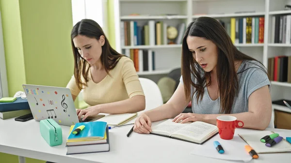 Dos Mujeres Sentadas Mesa Estudiando Usando Libro Lectura Portátil Universidad —  Fotos de Stock
