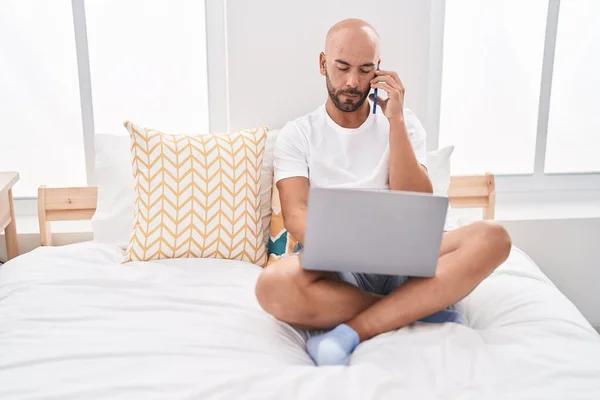 Young Bald Man Using Laptop Talking Smartphone Bedroom — 图库照片