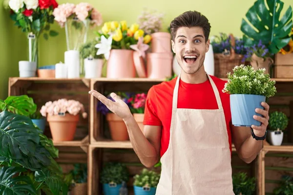 Jovem Hispânico Trabalhando Florista Loja Segurando Planta Celebrando Realização Com — Fotografia de Stock