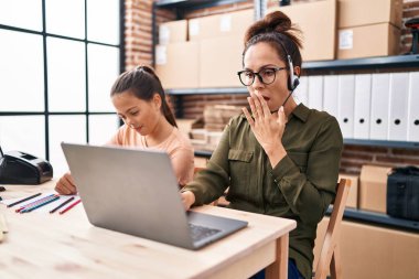 Genç anne ve kızı ofiste çalışıyor ve ödevlerini yapıyor. Ağızlarını eliyle kapatıyor, şok geçiriyor ve hata yapmaktan korkuyorlar. şaşırmış ifade 