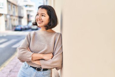 Young woman standing with arms crossed gesture looking to the side at street