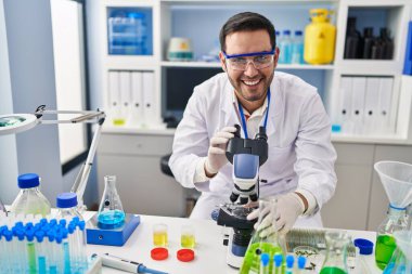 Genç İspanyol bilim adamı laboratuvarda mikroskop kullanıyor.