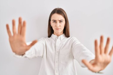 Kafkas 'lı genç bir kadın izole edilmiş arka planda duruyor. Avuçlarıyla jesti durduruyor. Öfkeli ve hayal kırıklığına uğramış bir ifadeyle. 