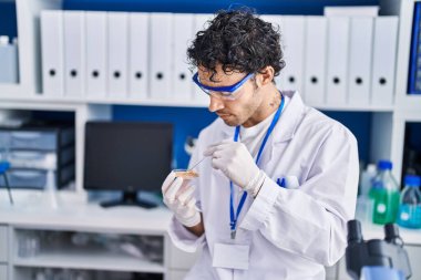 Genç İspanyol bilim adamı laboratuvarda cımbızla örnek tutuyor.