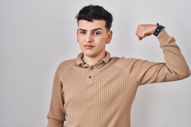 İzole edilmiş arka planda duran ikili olmayan kişi güçlü, kendine güvenen ve güçten gurur duyan biri. 